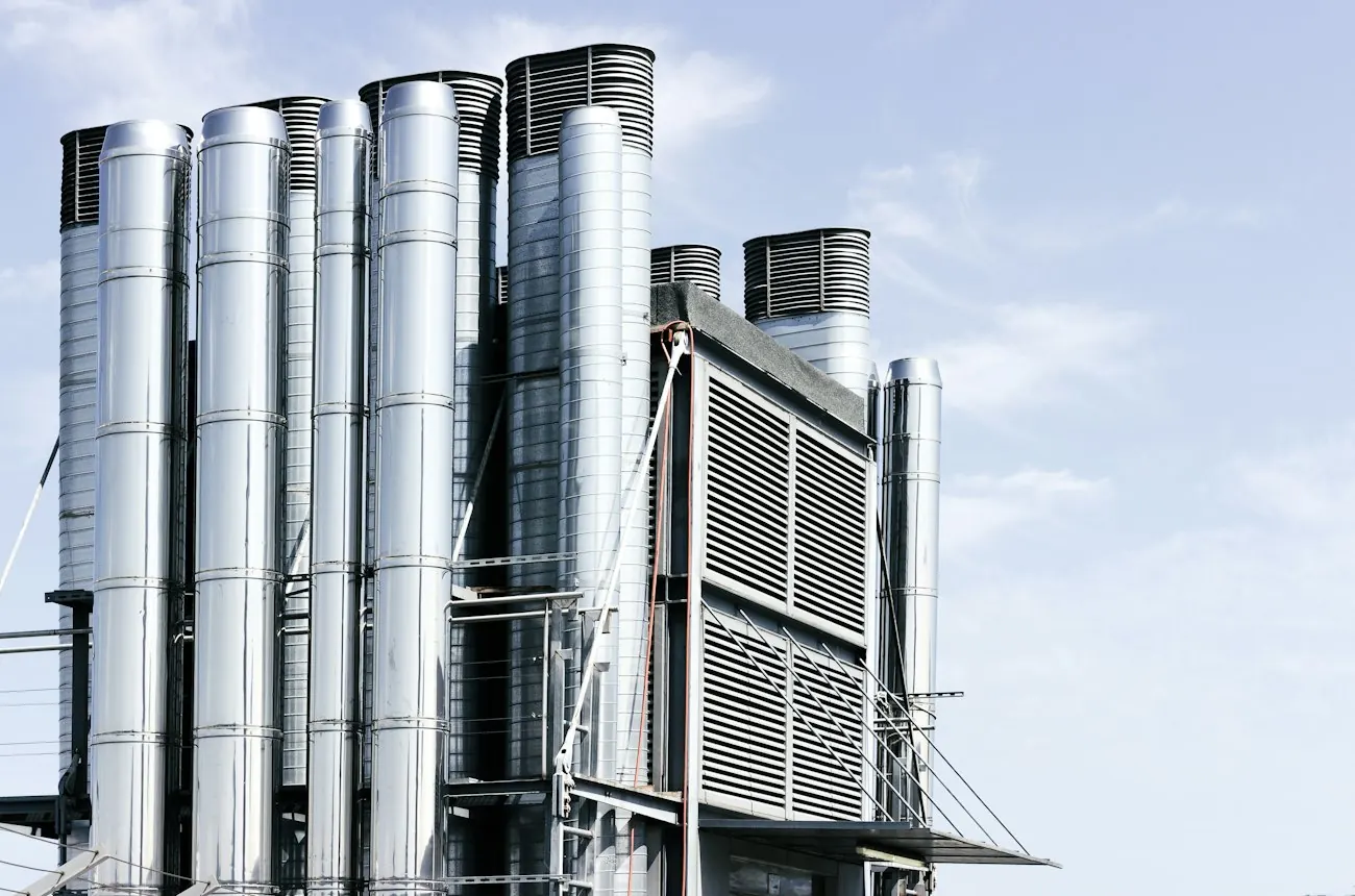Stainless steel ventilation stacks against a blue sky